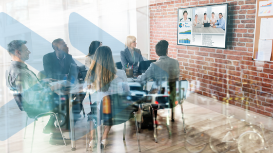 Meeting room with six people around a table, partaking in a video conference via tv on the wall. Overlay of Visions Dunedin logo.