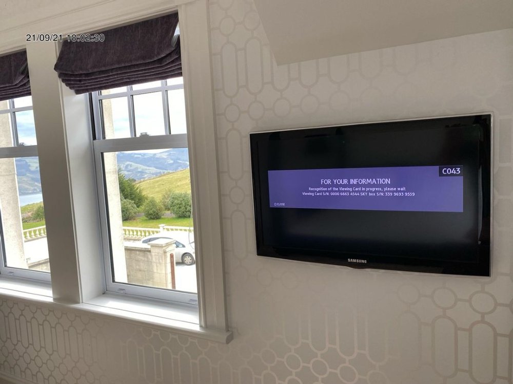 A room at camp estate, looking at the tv showing the guest information system, and out of the window with stunning harbour views