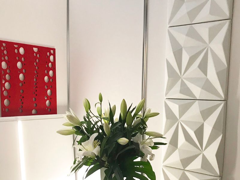 White walled corner in an office space, with white acoustic panels mounted to the wall
