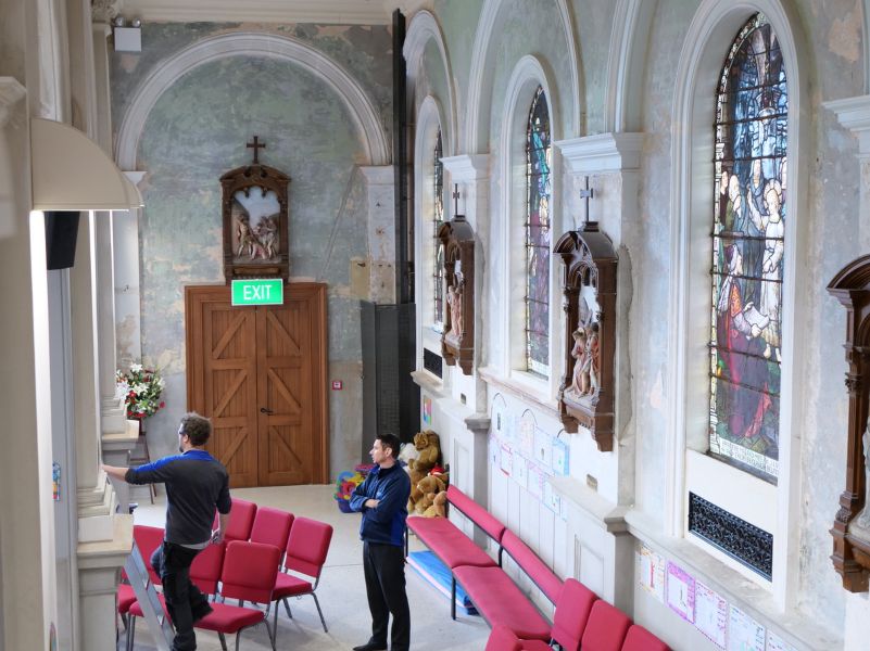 Neville and Andrew stand in the church, looking towards the altar, during installation